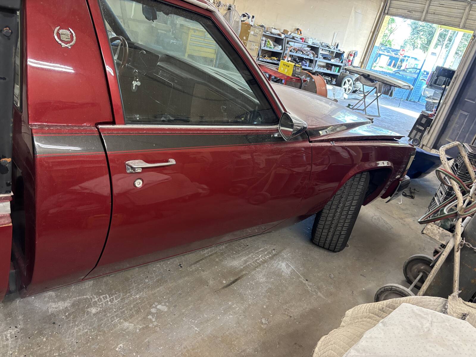 A dark red classic Cadillac coupe inside the shop for restoration work.