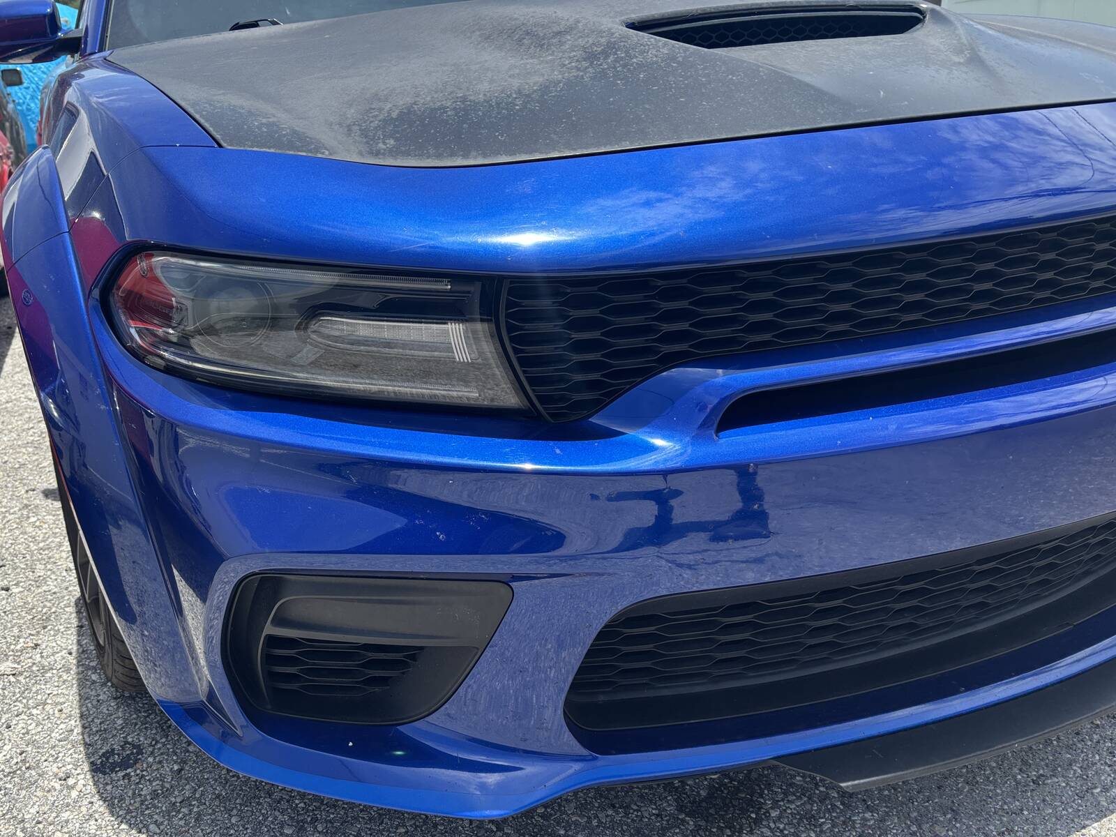 A blue muscle car with its front end rebuilt and back in one piece at the shop.