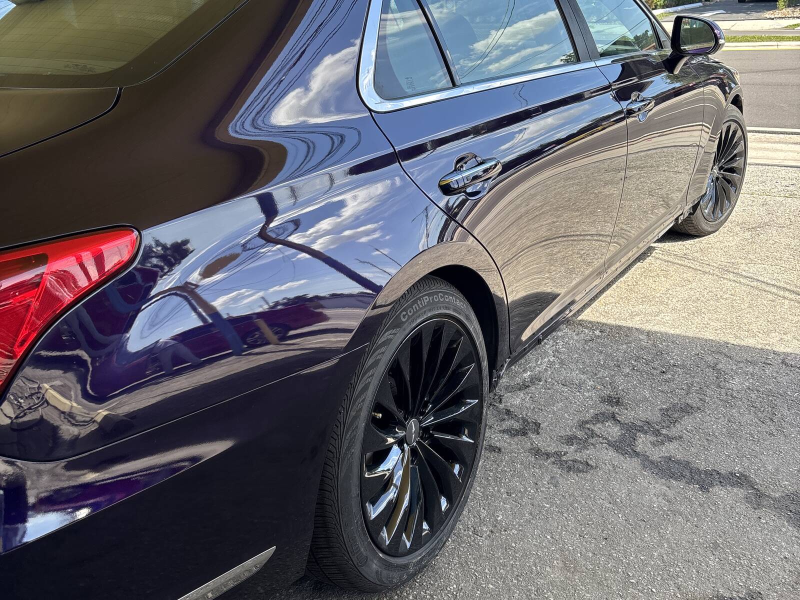 A dark purple sedan with a fresh, glossy paint job, parked outside the shop.