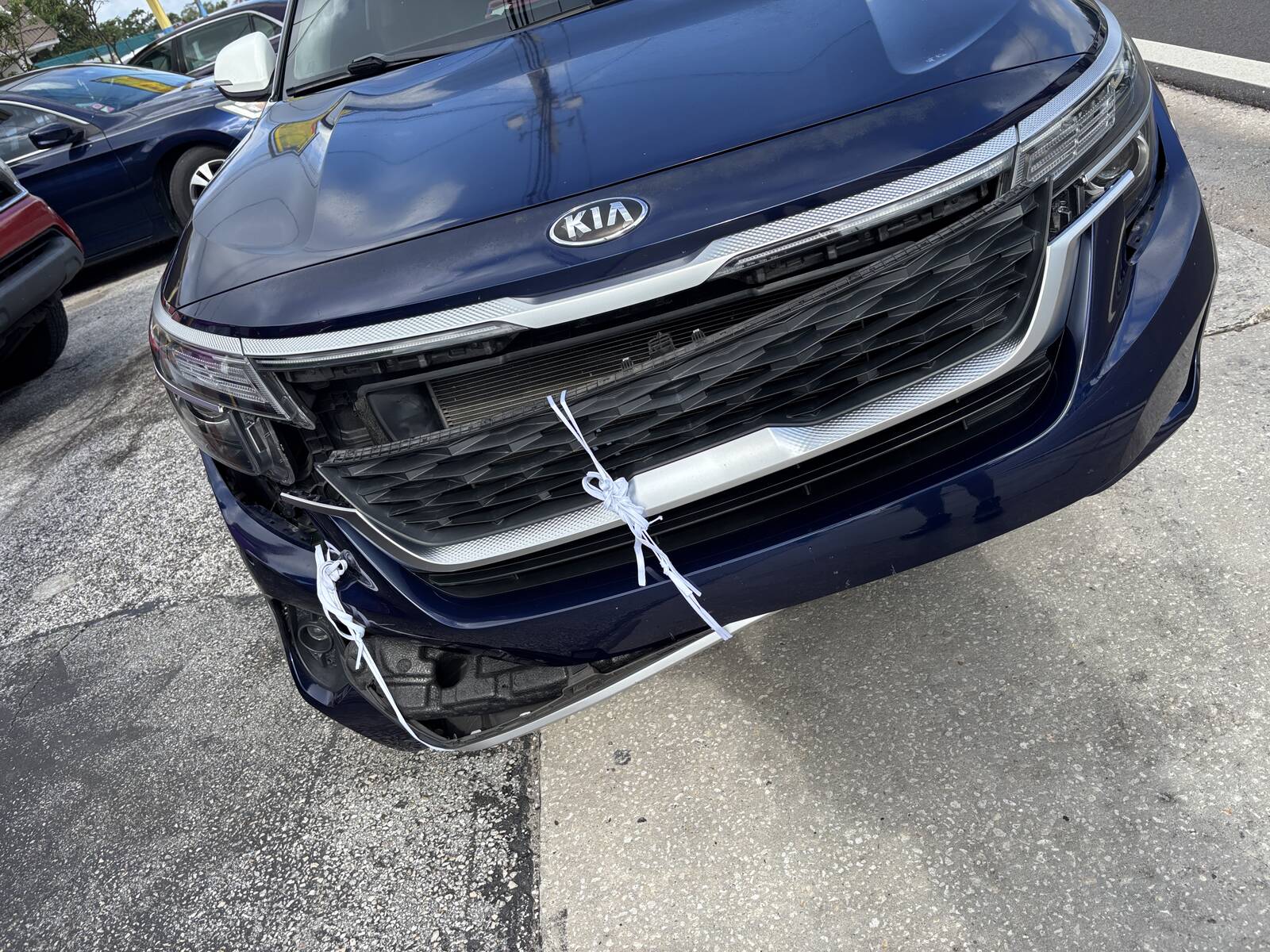 A dark blue SUV that came in with its front bumper tied on after a hit.